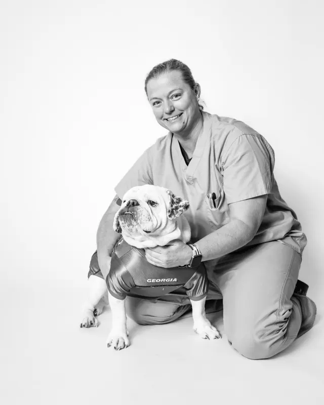 Dr. Courson kneeling beside an English bulldog wearing a Georgia jersey